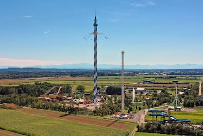 Blick über den Freizeitpark Skyline Park mit 150 Meter hohem Turm mit Kettenkarussell, im Hintergrund Berge