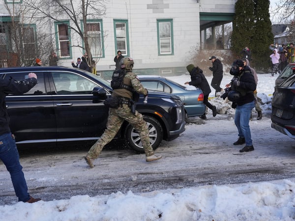 A federal agent runs towards protesters trying to block vehicles from leaving the scene after a driver of a vehicle was shot in Minneapolis, Minnesota, U.S., January 7, 2026.  REUTERS/Tim Evans