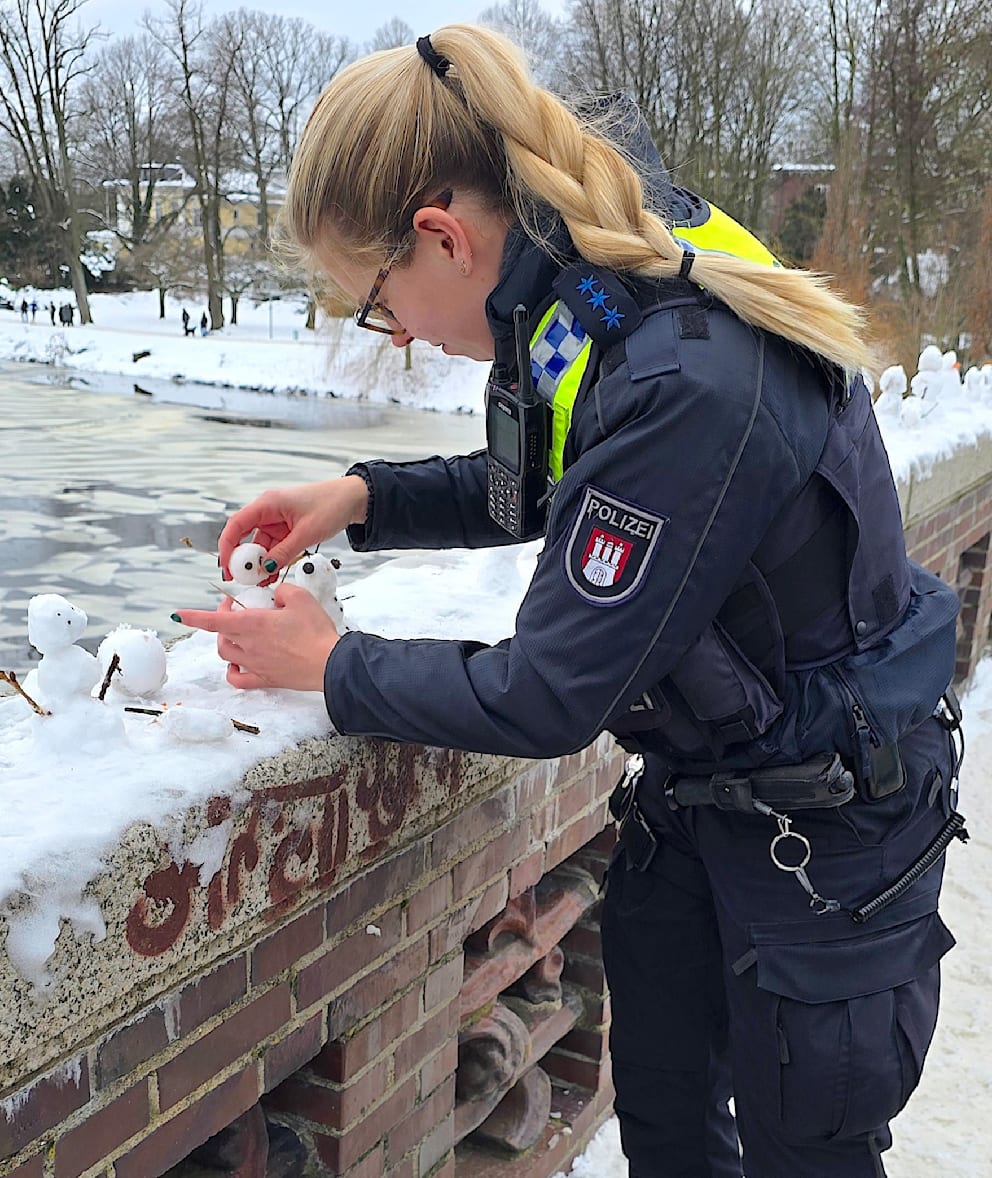Eine Polizistin stellt auch einen neuen Schneemann auf die Brücke an der Alster
