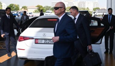 Die russische Delegation verlässt das Hotel in Abu-Dhabi zu Verhandlungen über den Ukraine-Krieg. Mehrere Männer in dunklen Anzügen stehen und gehen um ein weißes Auto herum.