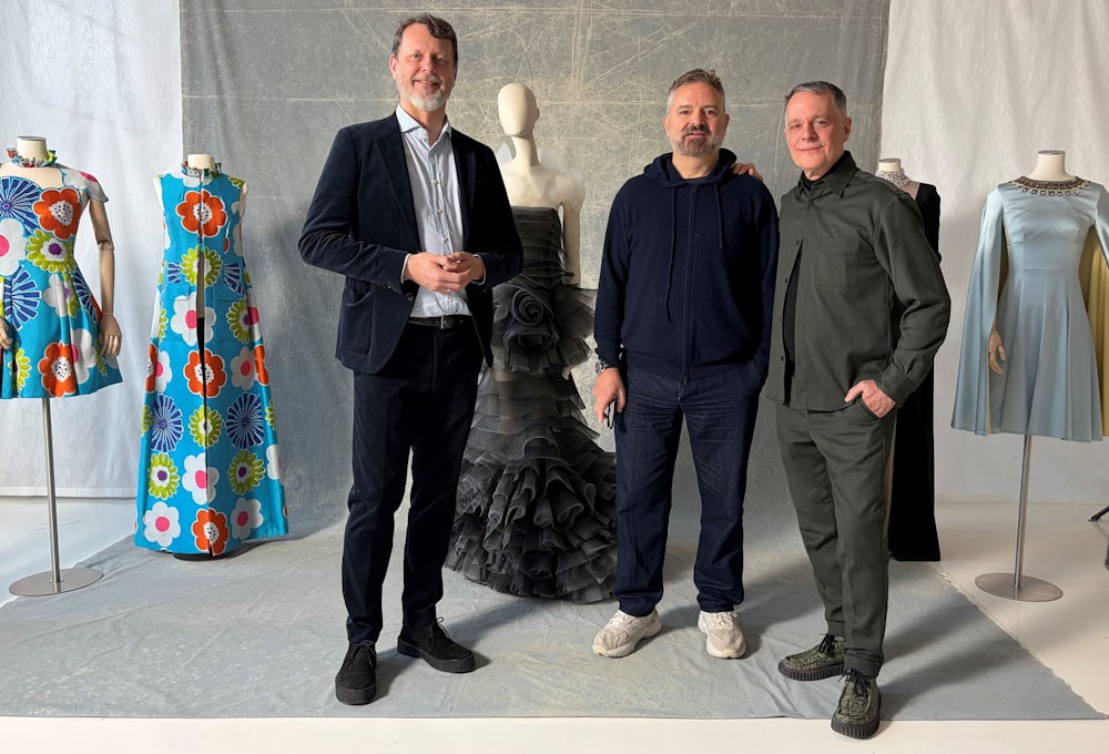 Museumsdirektor Karl Borromäus Murr (links) mit Adrian Runhof (Mitte) und Johnny Talbot bei der Übergabe der Couture ans tim in Augsburg. Amal Clooney ist ebenso ein Fan des Designs, das  links zu sehen ist, wie Claudia Roth, frühere Staatsministerin für Kultur und Medien.