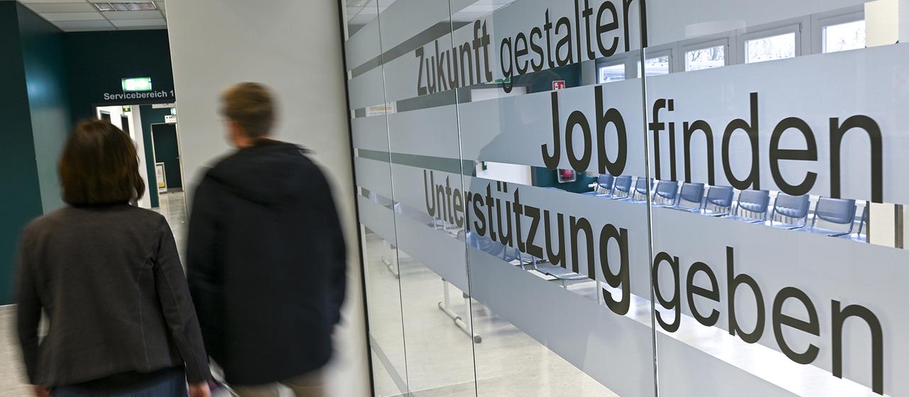 Menschen gehen in den Gängen einer Agentur für Arbeit. | dpa Menschen gehen in den Gängen einer Agentur für Arbeit.
