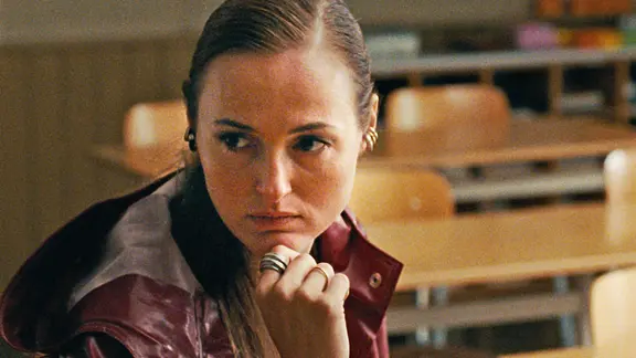 Eine Frau mit braunen Augen und langen Haaren schaut nachdenklich und freundlich zugleich - Szene aus "Armand"