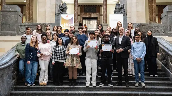 Jugendliche, die als A-Team Mitglieder der Stadt Hannover ausgezeichnet wurden, stehen zusammen mit Oberbürgermeister Belit Onay (Grüne) vor dem Rathaus.