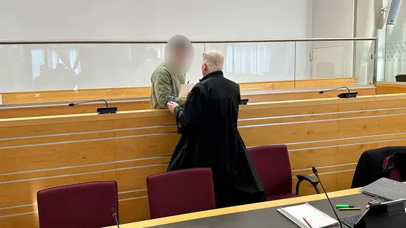 Ein Angeklagter spricht bei einem Prozess im Landgericht Hannover mit einer Person. | NDR, Sandrine Harder Ein Angeklagter spricht bei einem Prozess im Landgericht Hannover mit einer Person.