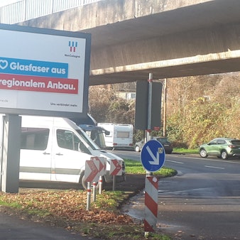 Autos parken zwischen den Pfeilern einer Hochbahntrasse.