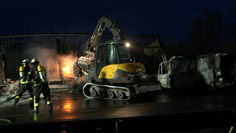 Mit einem Bagger werden brennende Papierrollen aus dem verunglückten Laster gezogen, die Feuerwehr löschte bis zum Morgen