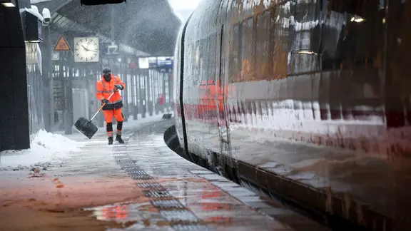 Winterdienst-Mitarbeiter schieben Schnee von einem Bahnsteig am Hamburger Hauptbahnhof.