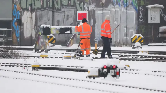 Mitarbeiter befreien Weichen und Gleise der Deutschen Bahn von Schnee und Eis im Hauptbahnhof Hannover. | dpa, Julian Stratenschulte Mitarbeiter befreien Weichen und Gleise der Deutschen Bahn von Schnee und Eis im Hauptbahnhof Hannover.