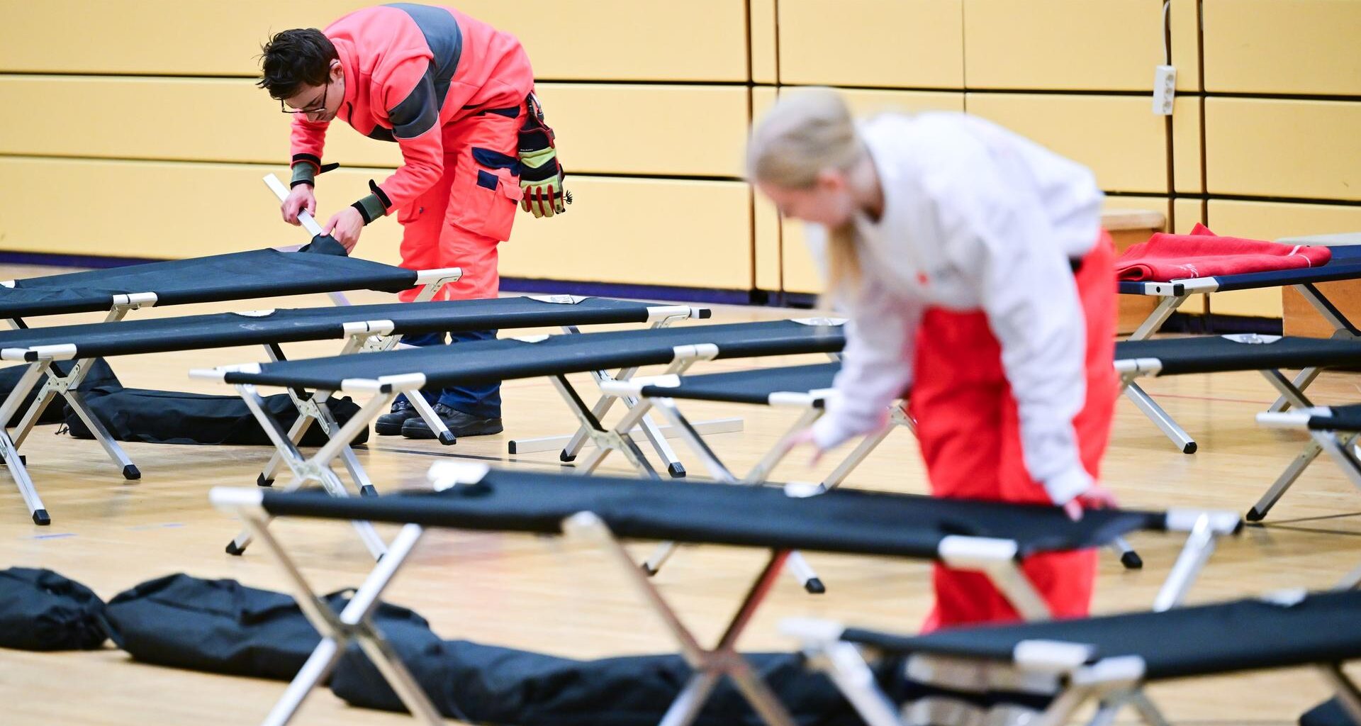Ehrenamtliche Mitarbeiter des Roten Kreuzes bauen während eines Stromausfalls im Südwesten Berlins in einer Notunterkunft Feldbetten auf.