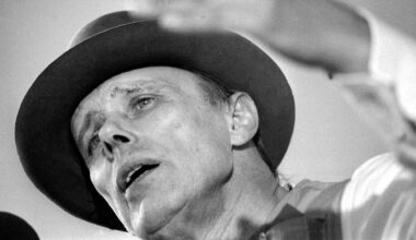 Der Künstler Joseph Beuys in Untersicht auf einem Schwarz-Weiß-Foto. Er diskutiert.