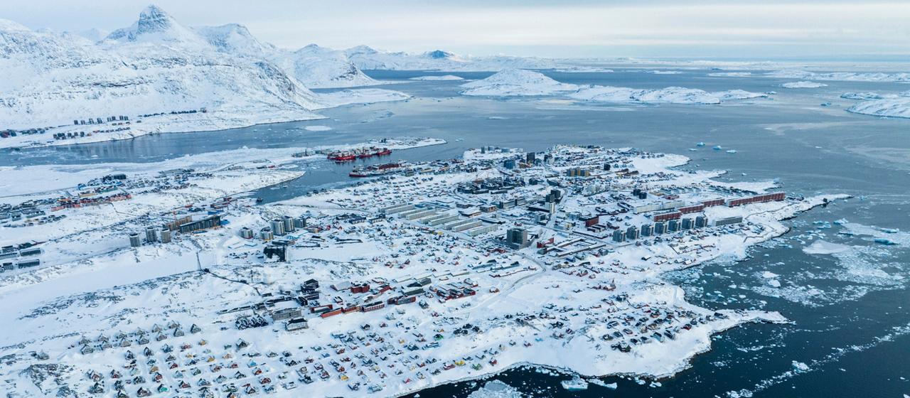 Luftaufnahme vom schneebedeckten Nuuk, Grönland mit Eisschollen im Wasser.