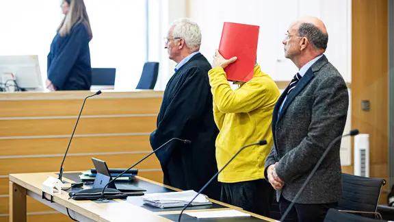 Ein Angeklagter (Mitte) steht neben seinem Verteidiger Matthias Jochmann (links) im Landgericht Braunschweig.