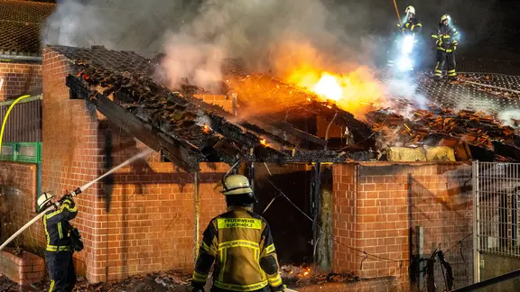 Das Feuer war kurz nach Mitternacht aus bislang ungeklärter Ursache im Eingangsbereich der Sporthalle ausgebrochen. | JOTO Die Feuerwehr löscht den brennenden Eingangsbereich einer Sporthalle in Buchholz.