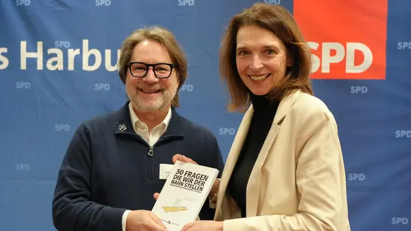 Reini Crasemann übergibt das Buch der Bürgerinitiative Y-Monster "50 Fragen, die wir der Bahn stellen würden, wenn wir Verkehrsminister wären" an die Bundestagsabgeordnete Svenja Stadler (SPD). | Bürgerinitiative Y-Monster Bürgerinitiative Y-Monster übergibt ihr Buch an MdB Svenja Stadler.