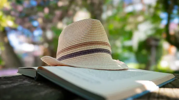 Hut auf einem aufgeschlagenem Buch, an einem schattigen Plätzchen im Garten