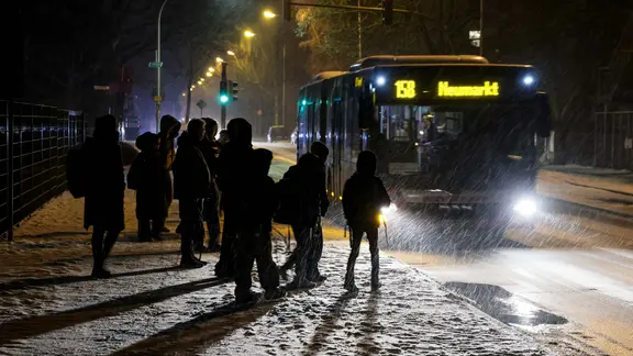 Passanten und Schüler warten im Schneetreiben an der Haltestelle Eversburg auf den Bus nach Osnabrück.