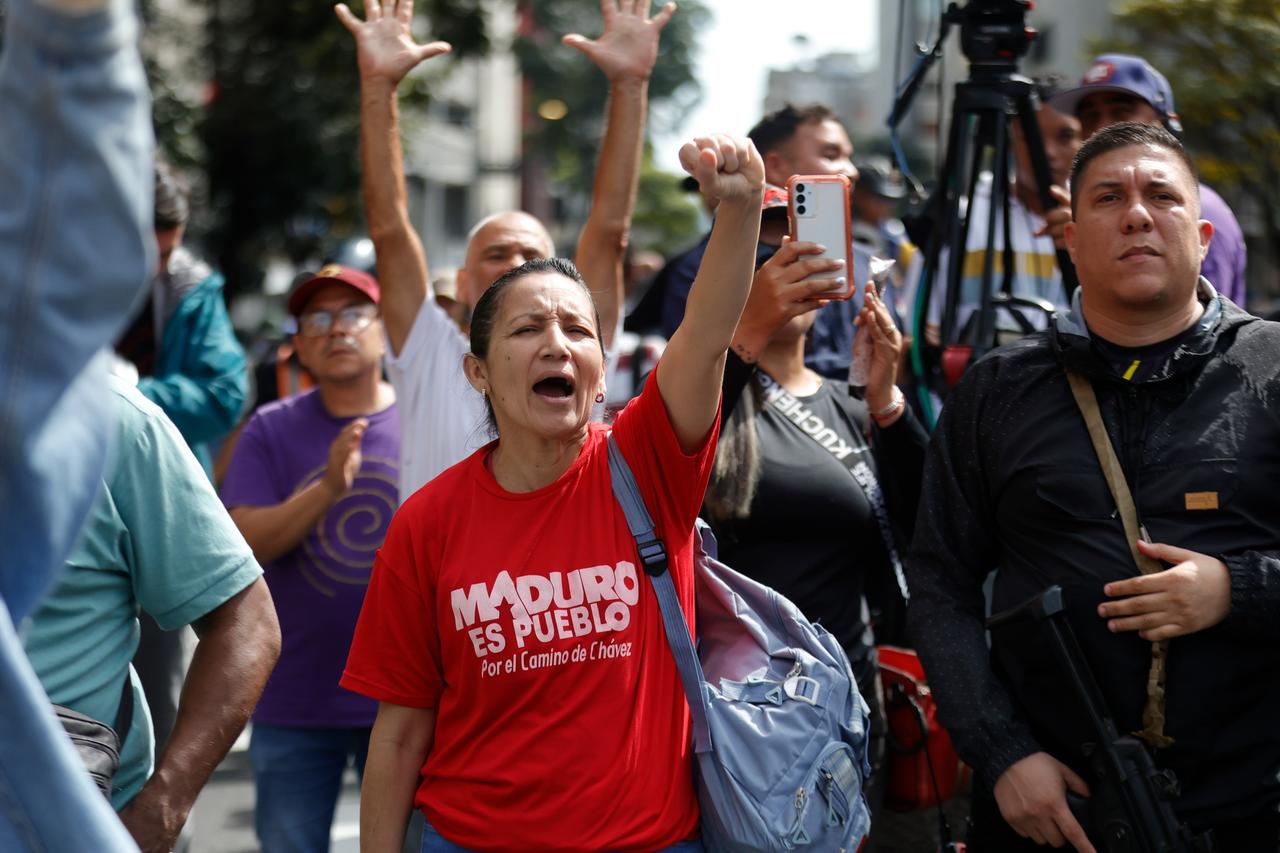 Mehrere Menschen schreien und recken die Arme in die Höhe. Auf dem T-Shirt einer Frau steht: "Maduro ist das Volk".