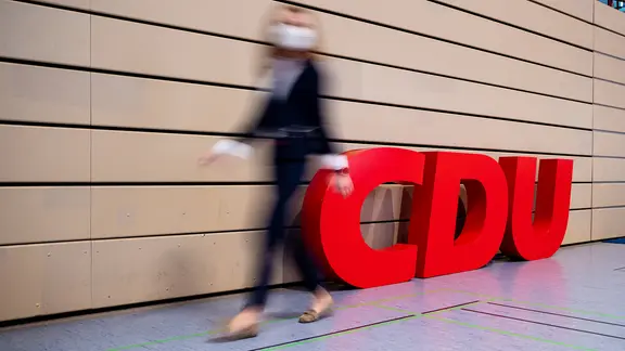 Eine Frau geht am Logo der CDU vorbei. | dpa-Bildfunk, Moritz Frankenberg Eine Frau geht am Logo der CDU vorbei.