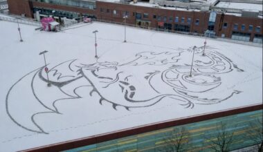 Aus dem Schnee schaut einem ein feuerspeiender Drache entgegen.