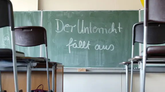 Auf einer Tafel in eine leeren Schulklasse steht "Der Unterricht fällt aus". | picture alliance / photothek | Thomas Imo Auf einer Tafel in eine leeren Schulklasse steht "Der Unterricht fällt aus".