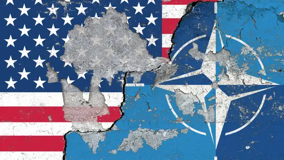 Die Nationalflagge der USA und das Logo der NATO auf einer Wand mit abgeplatzter Wandfarbe und einem grossen Riss. | SULUPRESS.DE/Torsten Sukrow Die Nationalflagge der USA und das Logo der NATO auf einer Wand mit abgeplatzter Wandfarbe und einem grossen Riss.