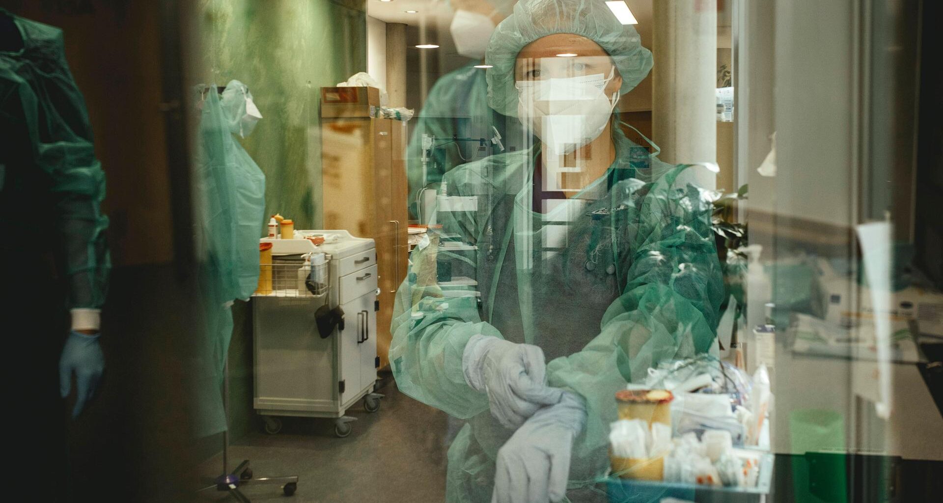 Ärzte vor Betreten der Covid-Station. Sie tragen Schutzkleidung und ziehen sich Handschuhe an.