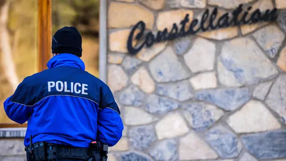 Ein Polizist steht nach einem Feuer vor der Bar Le Constellation in Crans-Montana