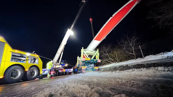 Ein verunfallter Schwertransporter mit Windflügel steht am Straßenrand