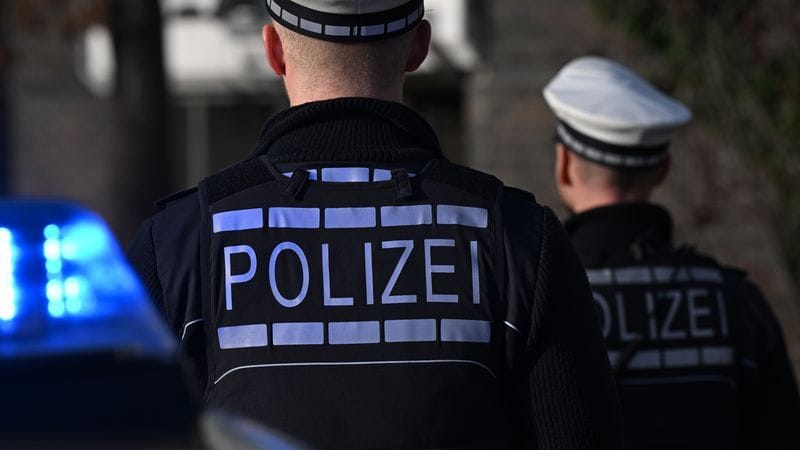 Das Logo der Polizei auf der Dienstkleidung von Polizisten, die vor einem Blaulicht stehen (Symbolbild): Rund 5.000 Menschen haben an der Demonstration in Frankfurt teilgenommen.