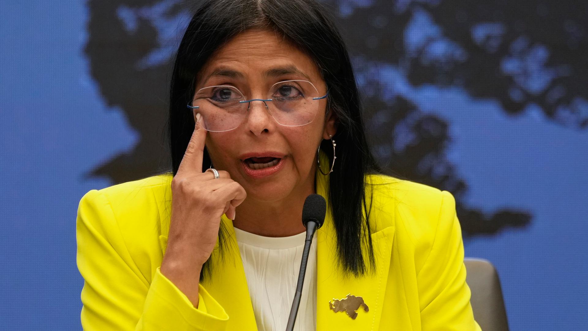 Delcy Rodríguez auf einer Pressekonferenz im Präsidentenpalast in Venezuelas Hauptstadt Caracas. Sie zeigt mit dem rechten Zeigefinger neben ihr rechtes Auge. 