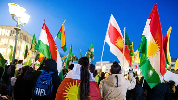 Menschen laufen mit schwenkenden Fahnen auf einer Demonstration mit.