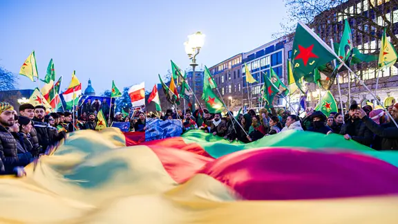 Mehrere Demonstranten halten eine große Fahne auf dem Opernplatz in Hannover. | dpa-Bildfunk, Moritz Frankenberg Mehrere Demonstranten halten eine große Fahne auf dem Opernplatz in Hannover.