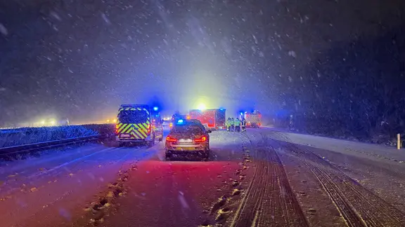 Einsatzfahrzeuge stehen bei starkem Schneefall auf der A2.