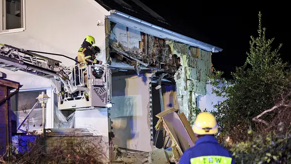 Einsatzkräfte von Feuerwehr und THW arbeiten an einem Haus nach einer Explosion. 