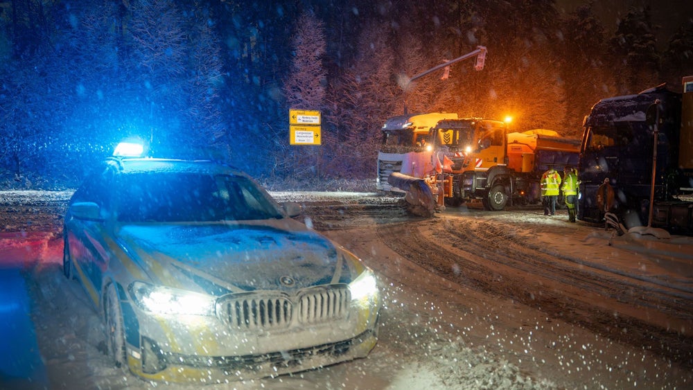 Während ein Streufahrzeug den Kreuzungsbereich an der Auffahrt zur A6 bei Nürnberg räumt, sperrt die Polizei die Zufahrt.