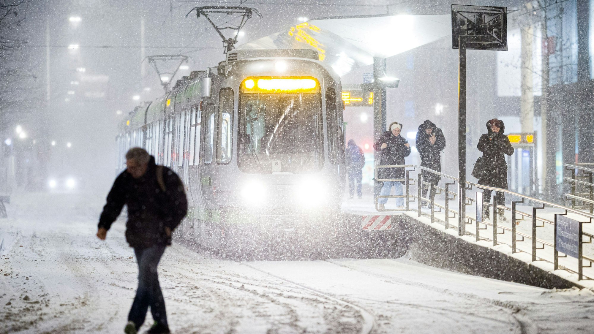 Das Bild zeigt eine Straßenbahn am frühen Morgen im dichten Schneefall an einer Haltestelle im Zentrum von Hannover. Foto: Moritz Frankenberg/dpa