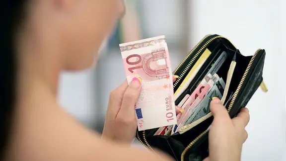Eine Frau hält ein offenes Portemonnaie in den Händen.