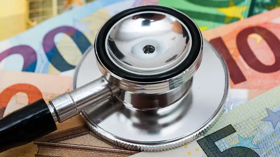 Ein Stethoskop liegt auf Geldscheine.