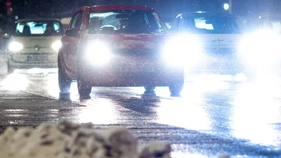 Mehrere Autos sind bei winterlichem Wetter auf glatter Fahrbahn unterwegs.