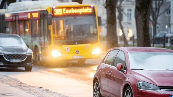 Ein Linienbus ist bei leichtem Schneefall auf einer Straße in Oldenburg unterwegs.