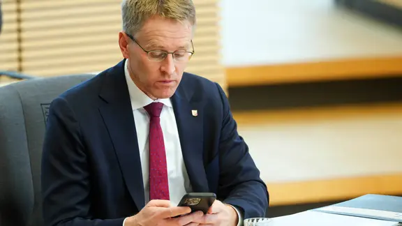 Daniel Günther (CDU) schaut auf sein Handy
