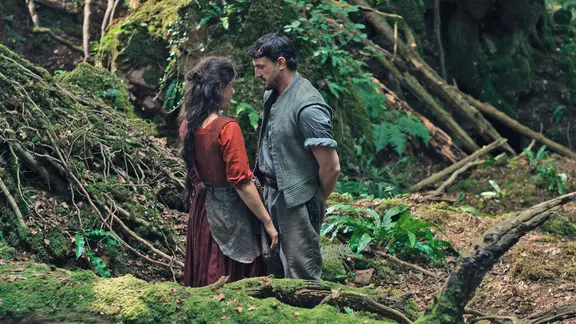 Jessie Buckley (links) spielt Agnes, die sich auf den ersten Blick in den Lateinlehrer William Shakespeare (Paul Mescal) verliebt: in "Hamnet". | Focus Features Release Jessie Buckley und Paul Mescal stehen im Wald - Szene aus "Hamnet" von Chloé Zhao