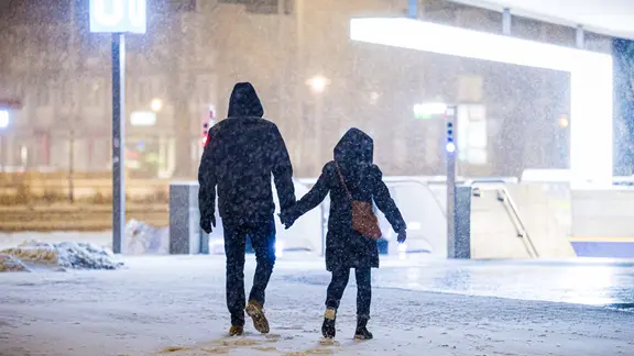 Zwei Menschen gehen in Hannover im dichten Schneefall zur U-Bahn