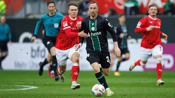 Hannovers Maurice Neubauer (m.) im Zweikampf mit Kaiserslauterns Naatan Skyttae | picture alliance / Eibner-Pressefoto Hannovers Maurice Neubauer (m.) im Zweikampf mit Kaiserslauterns Naatan Skyttae