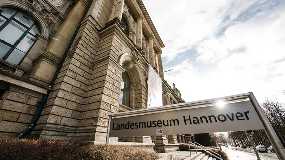 Vor einem Gebäude steht ein Schild mit der Aufschrift Landesmuseum Hannover.