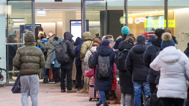 Zahlreiche Menschen stehen am Hauptbahnhof Hamburg in einer langen Schlange an einem Reisezentrum an. 