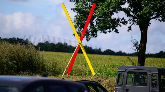 Ein Kreuz steht als Protest gegen eine geplante Neubaustrecke der Bahn auf einem Hof beim «Heidegipfel» zu dem die Bürgerinitiativen Pro-Alpha-E und der Projektbeirat Alpha-E eingeladen haben. | picture alliance/dpa, Philipp Schulze Ein Kreuz steht als Protest gegen eine geplante Neubaustrecke der Bahn auf einem Hof beim «Heidegipfel» zu dem die Bürgerinitiativen Pro-Alpha-E und der Projektbeirat Alpha-E eingeladen haben.