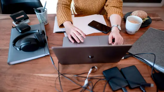 Eine Frau sitzt mit einem Laptop an einem Tisch im Homeoffice.