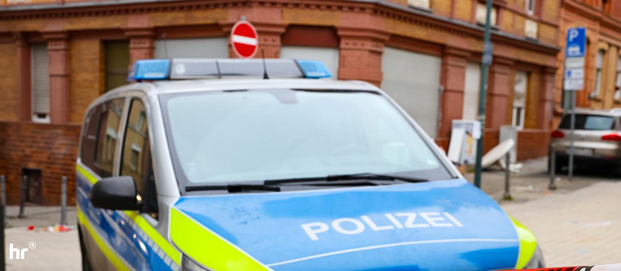 Polizeiliche Ermittlungen: Der Tatort in Wiesbaden ist abgesperrt | 5vision.news Polizeiauto steht an rot-weißer Polizeiabsperrung